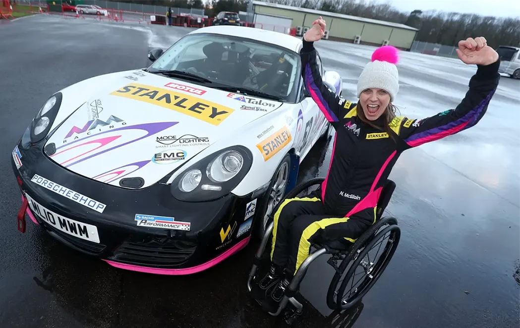 Personne en situation de handicap en fauteuil roulant vivant une expérience de sport automobile adapté de loisir sur circuit fermé